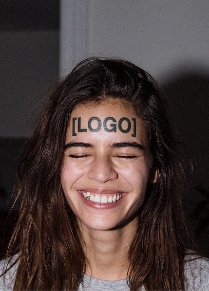 En leende kvinna med texten "[LOGO]" tatuerat i pannan.