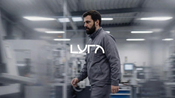 En man som går i en produktionsmiljö med Lyras logga centrerad i bilden