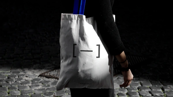 Tygpåse med blått handtag och Nordic Walls logotyp.